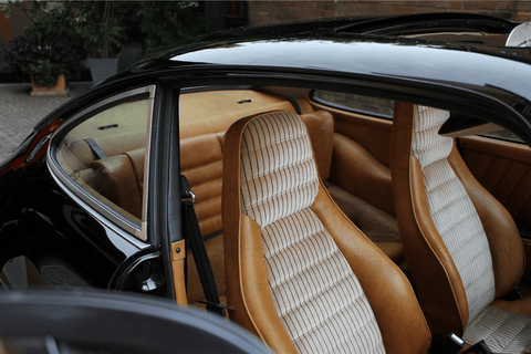 A pair of brown leather seats in the back of a car.