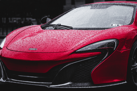 Red sports car with raindrops on the hood.