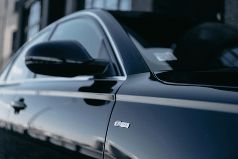 Audi S line badge on sleek silver car door with focused side mirror.