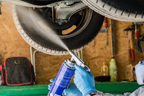 a person wearing a mask and gloves is spraying a car