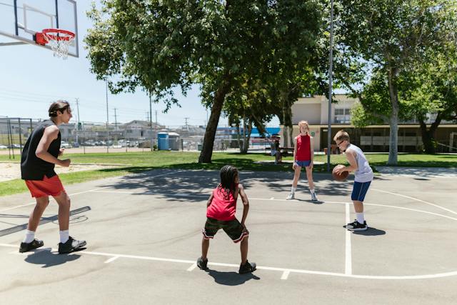 Adult with children playing basketball