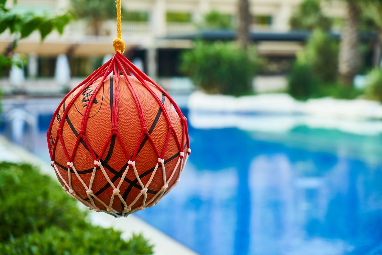 basketball inside a net hanging near the pool