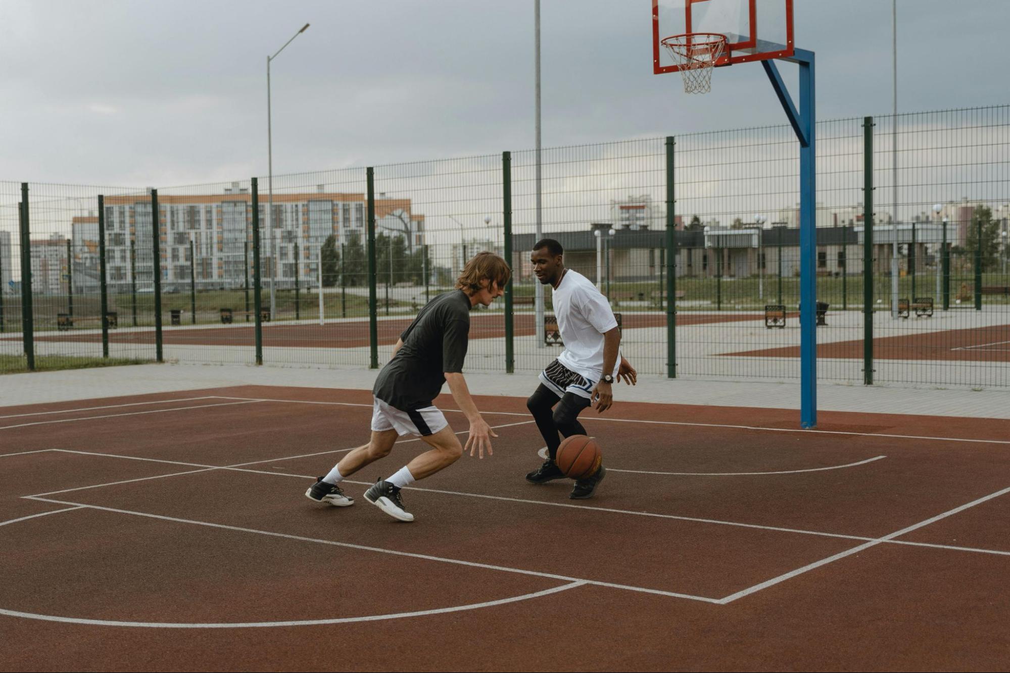 two men playing basketball outdoors