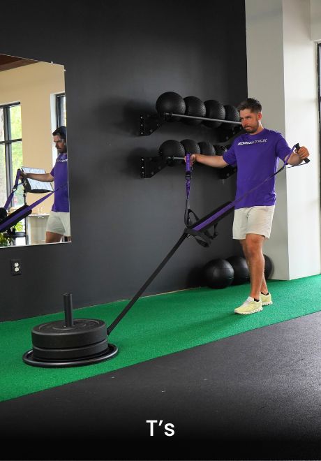 A man performs T's exercise with resistance band in a gym.