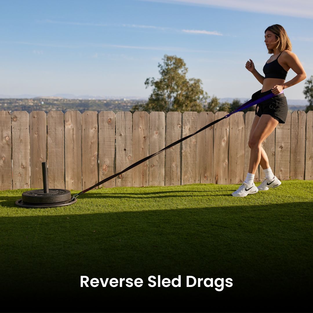 Woman doing reverse sled drags exercise in a backyard setting.