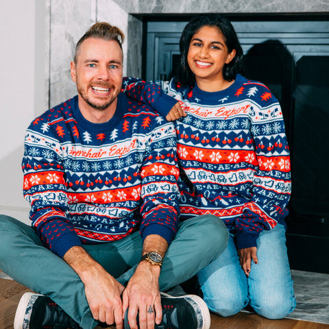 Armchair expert hosts Dax Shepard and Monica Padman pose in red, blue and white custom Christmas sweaters made by Roody sustainable swag