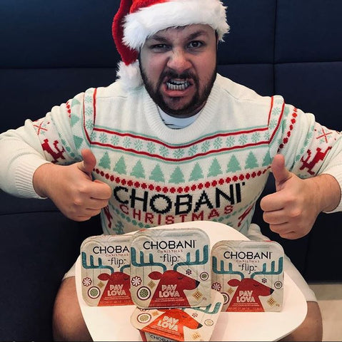 Team member from Chobani poses with two thumbs up in custom Christmas sweaters made by Roody sustainable swag
