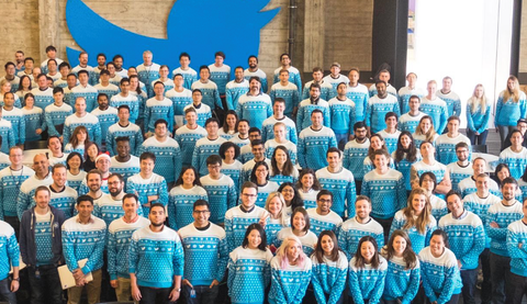 A large amount of the Twitter team gathered in front of the Twitter logo