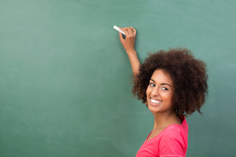 Female teacher explaining something to class in front of green chalkboard