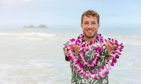 Man in custom Hawaiian shirt smiles at camera on beach