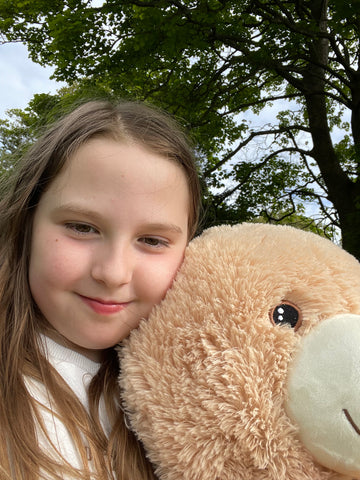 Selfie of a girl holding a large cuddly teddy bear.