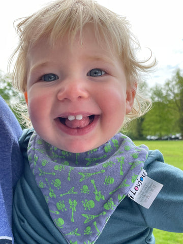 Close up of toddler smiling at the camera, showing two front teeth.