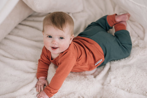 Baby wearing a merino pyjama top and cuff trousers.