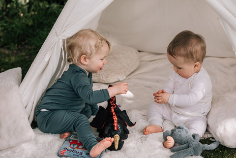 Two babies sitting up and playing in merino pyjamas