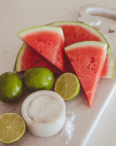 Watermelons next to limes on counter top