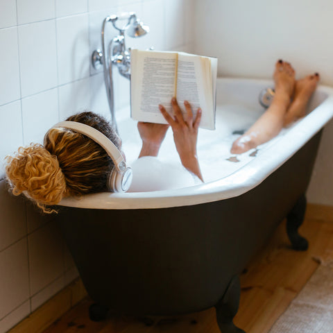 Girl reading in a tub full of bath foam bubbles