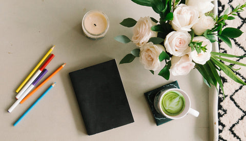 matcha drink with notebook candles pens and flowers