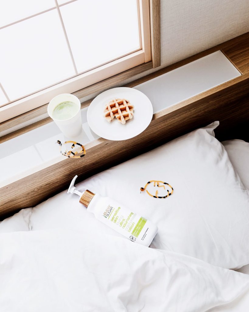 breakfast spread on bed next to lotion