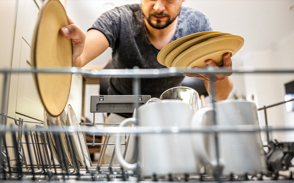 Mężczyzna układający naczynia w zmywarce - zdjęcie.