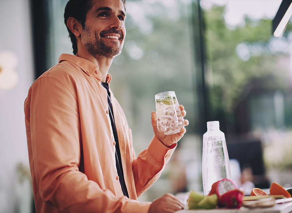 Uśmiechnięty mężczyzna trzymający szklankę z wodą gazowaną SodaStream - zdjęcie.