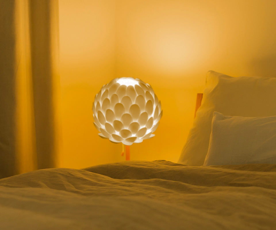 Lampka nocna przy łóżku zrobiona z plastikowych łyżeczek  - zdjęcie.