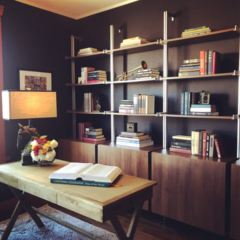 Office with dark walls and open walnut shelving.