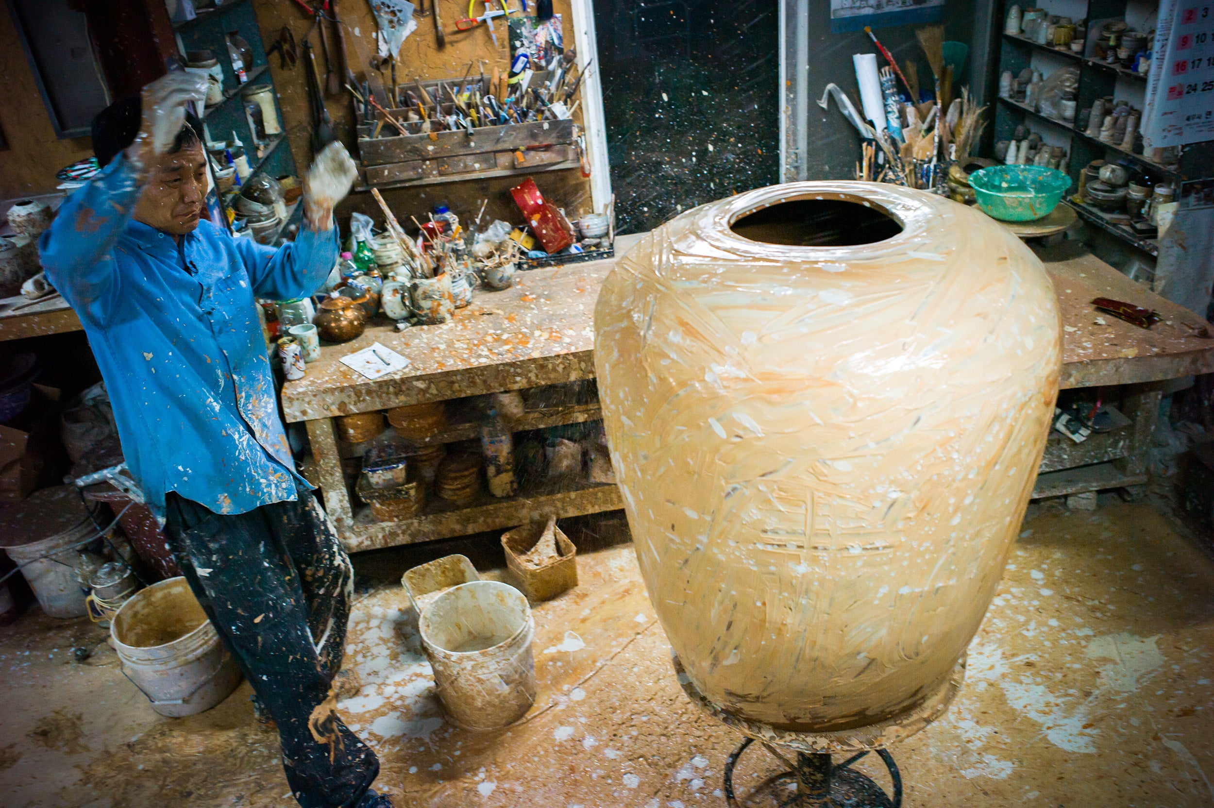 Kang-Hyo Lee decorating a giant Onggi jar at his studio in South Korea photographed by Jay Goldmark