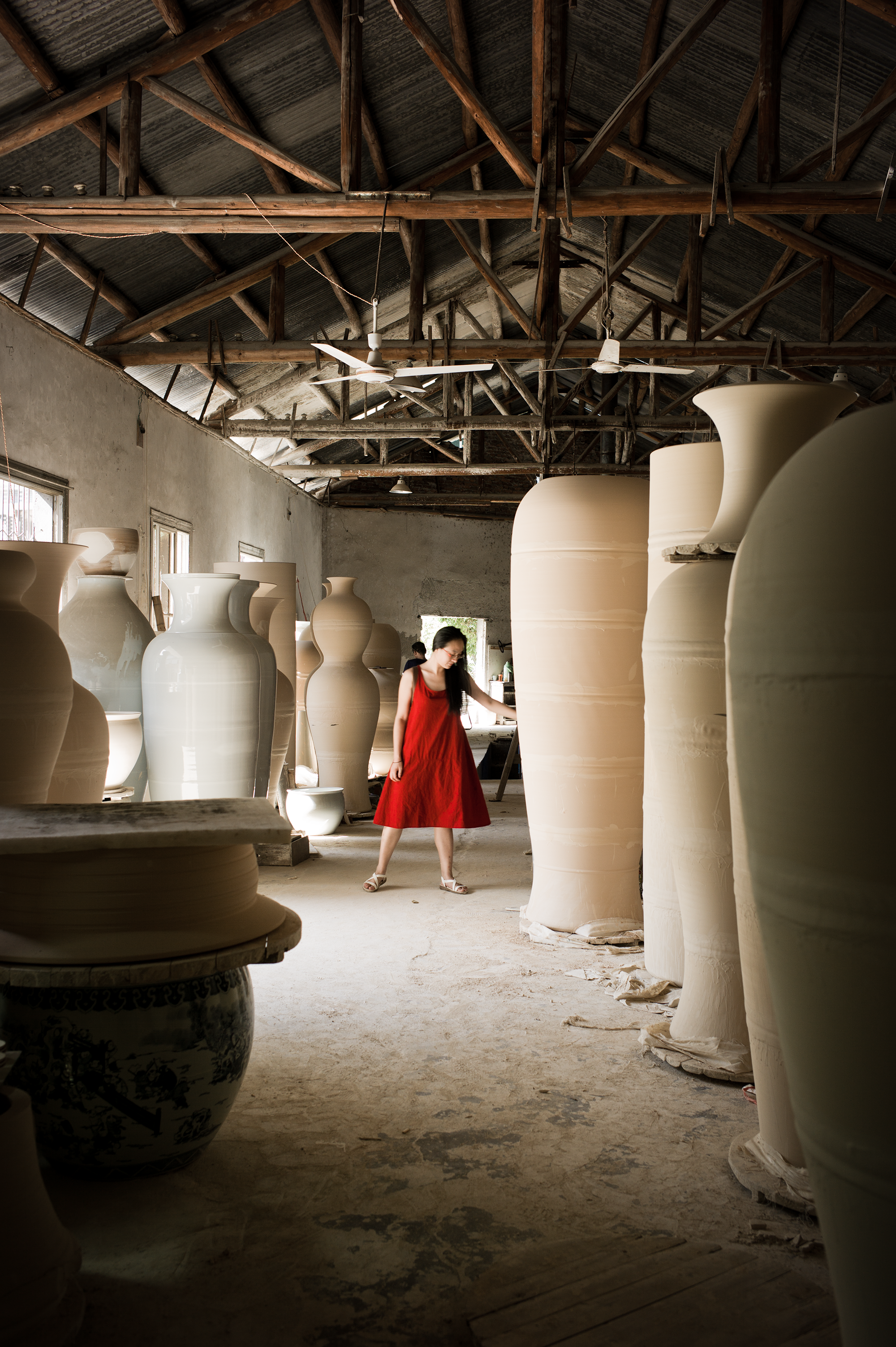 Baixu, Takeshi Yasuda's assistant, admires huge vases destined for glazing