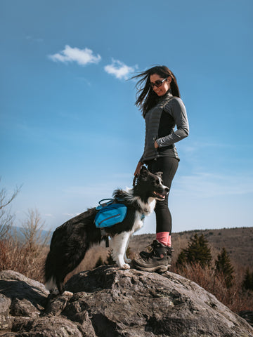 Kristina and Draco the border collie standing on a rock.