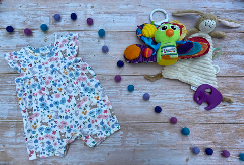 Little preloved floral romper and some baby toys on a flat lay