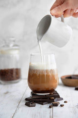 Person pouring milk into coffee