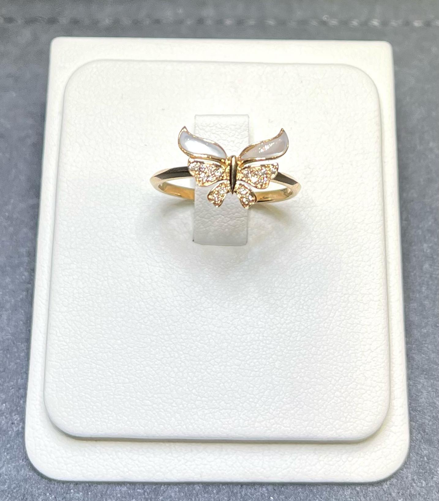 Gold diamond butterfly ring in a white ring holder