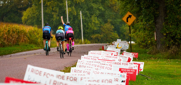 four people riding bicycles facing away from you