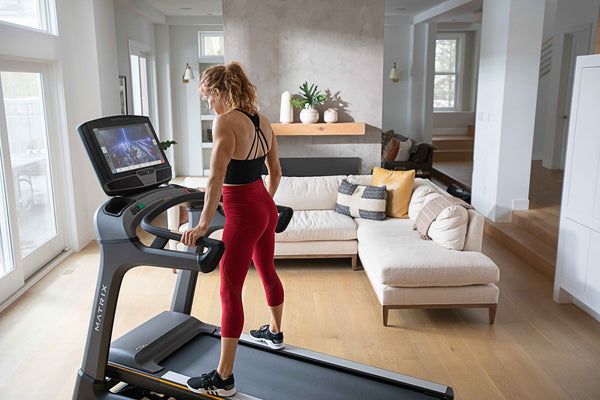 woman standing on a treadmill with a large screen