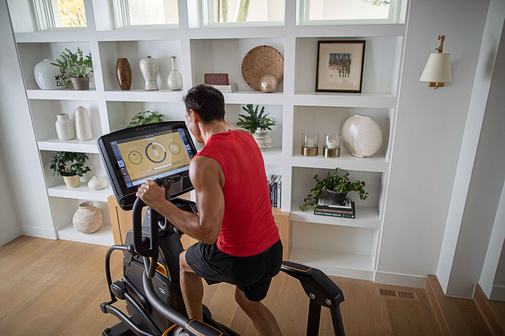 man on elliptical, facing away from camera, inside house