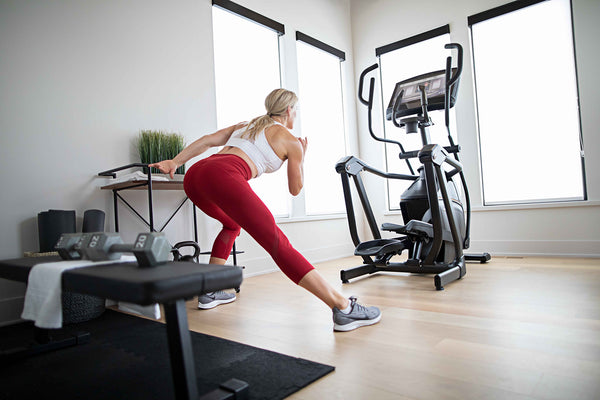 Woman squatting in front of an elliptical