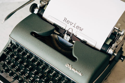 a typewriter and a paper with the word 'review' sticking out from it