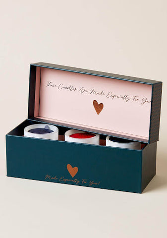A navy blue box containing three candles. On the inside of the lid of the box, the text reads “These candles are made especially for you”