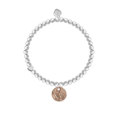 A silver bracelet with a gold charm featuring little baby feet.