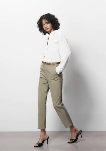 A woman wears cropped chino trousers, a white shirt, and black heels