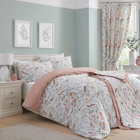 A bed with spring bedding in pastel colours of pinks and greens, featuring garden birds.