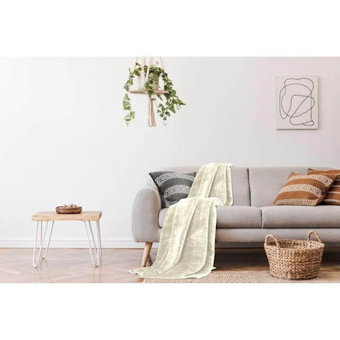 A bright and airy living room with a grey sofa, cream throw, a hanging plant and a wicker basket for storage.