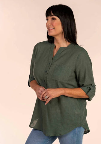A woman wears jeans and a dark green oversized blouse.