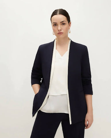 A woman wears black pants, a white top, and a black suit blazer.