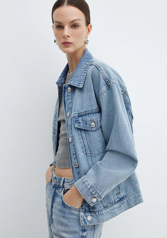 A woman wearing a denim jacket as an airport outfit.