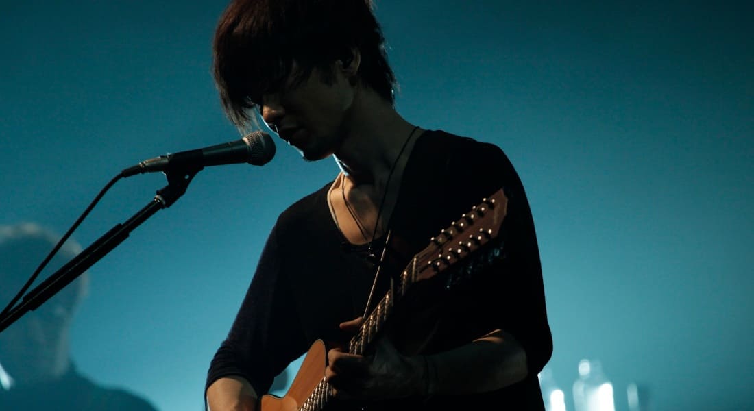 Toru Kitajima en train de chanter avec une guitare