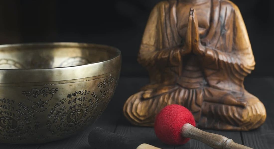 Un Bol Tibétain avec un Bouddha en bois qui prie