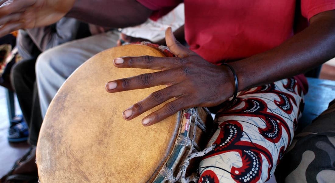 Un africain avec un tshirt rouge et un Djembé