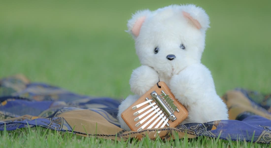 Un ours en peluche qui tient un petit Kalimba de 8 touches