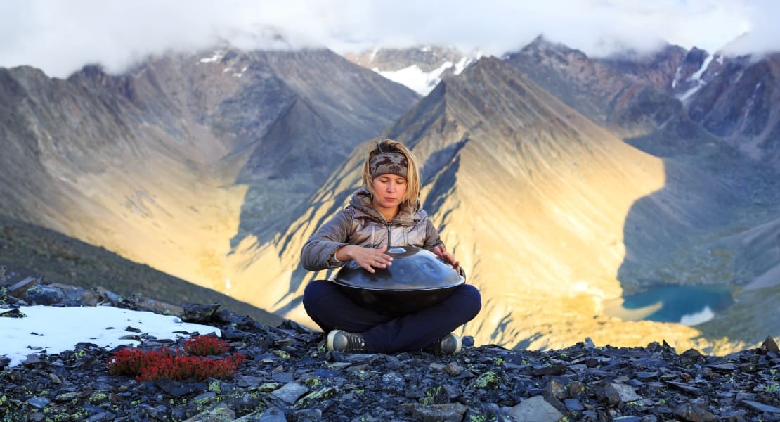 Une femme à la montagne jouant du Handpan